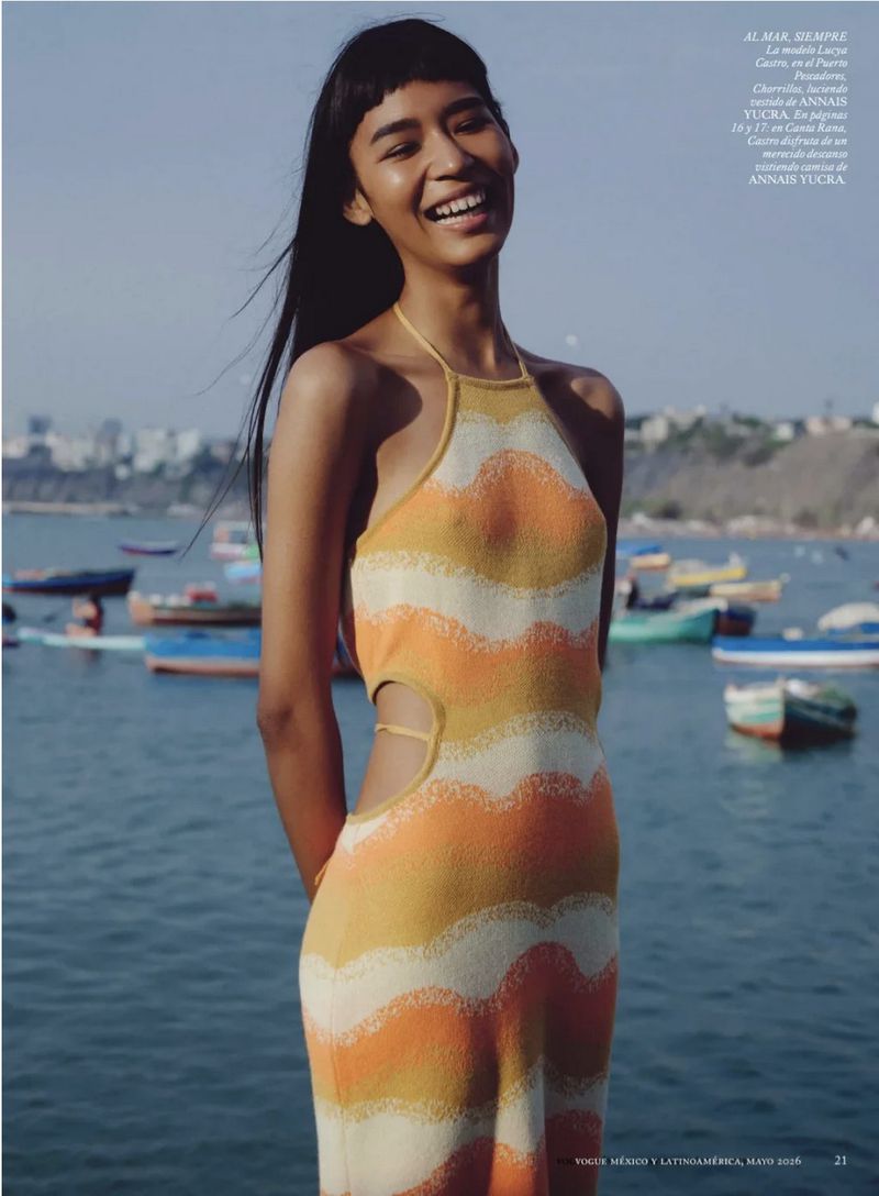 Smiling model in a striped halter dress standing outdoors by the ocean for a Vogue Mexico editorial