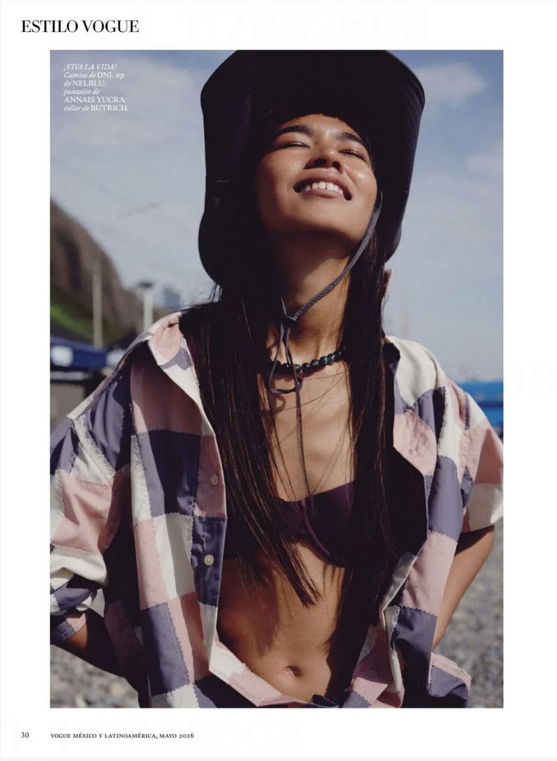 Smiling model wearing a dark bucket hat and a patchwork shirt outdoors under a clear sky for Vogue Mexico