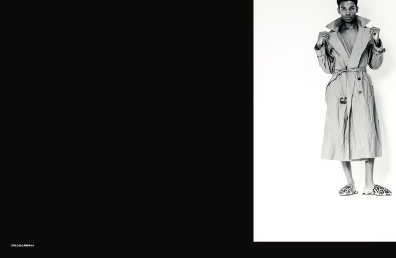 Model wearing a belted trench coat and patterned slip-on shoes against a white background with a solid black side panel