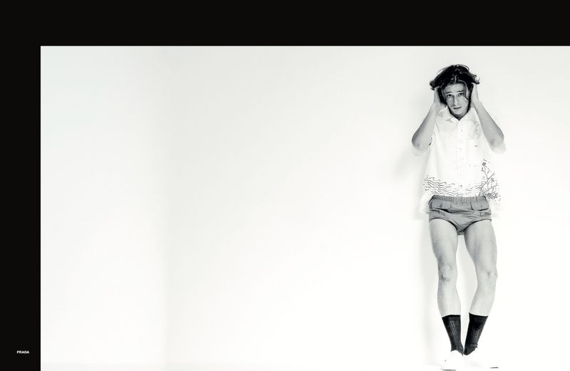 A young male model posing against a plain white studio background wearing patterned shorts and socks
