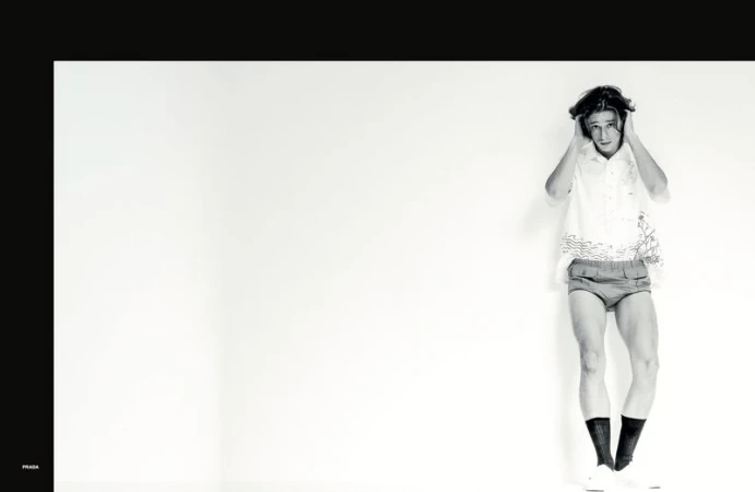 A young male model posing against a plain white studio background wearing patterned shorts and socks