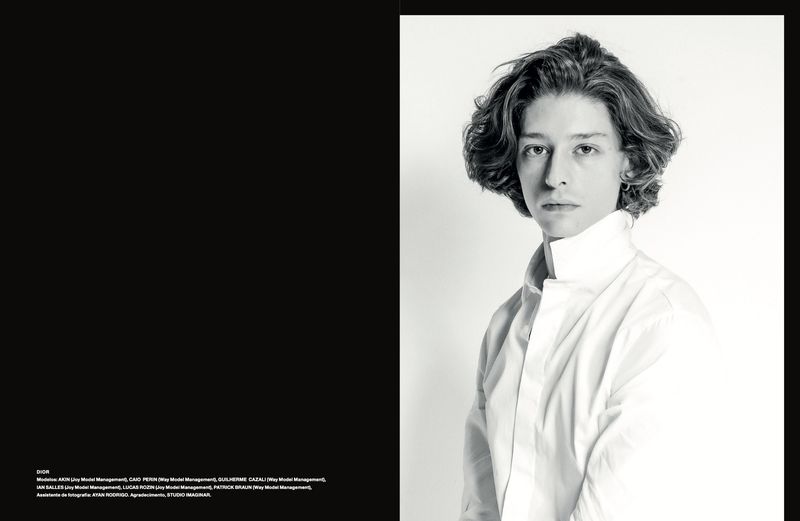Portrait of a male model with wavy hair wearing a white high-collar shirt against a white seamless background.