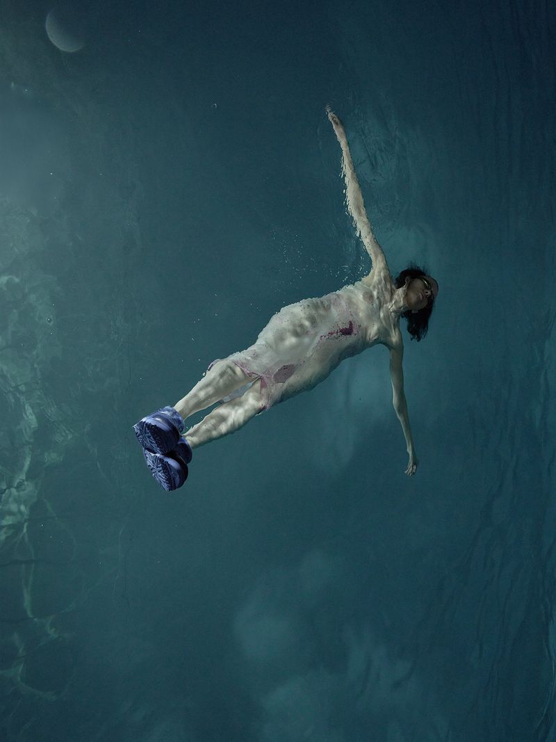 Underwater portrait of a woman floating in deep blue water wearing blue shoes