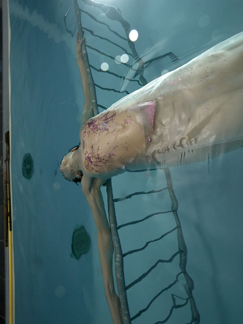Underwater portrait of a person submerged in a pool next to a metal ladder, captured for Re-Edition Magazine.