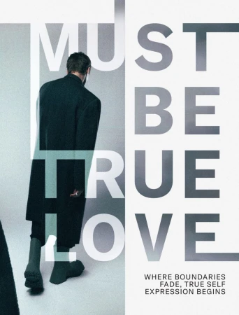 Man wearing a long dark coat and boots walking away against a neutral studio background with graphic typography