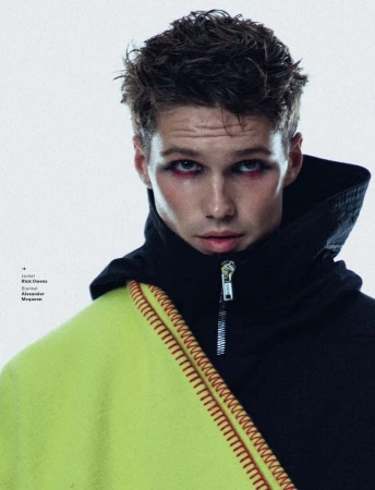 Portrait of Nick Truelove wearing a black hooded jacket and lime green blanket with red stitching for GQ South Africa