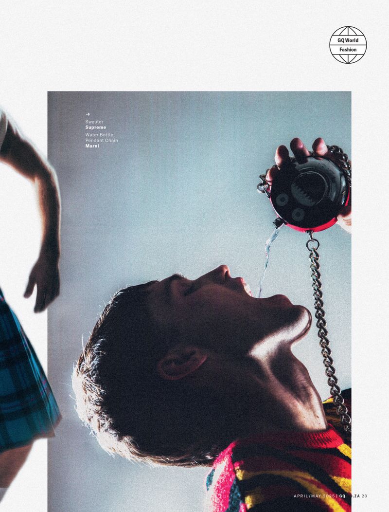 Editorial fashion image with a young adult male drinking water from a handheld container with chain detail, with a person in a kilt.