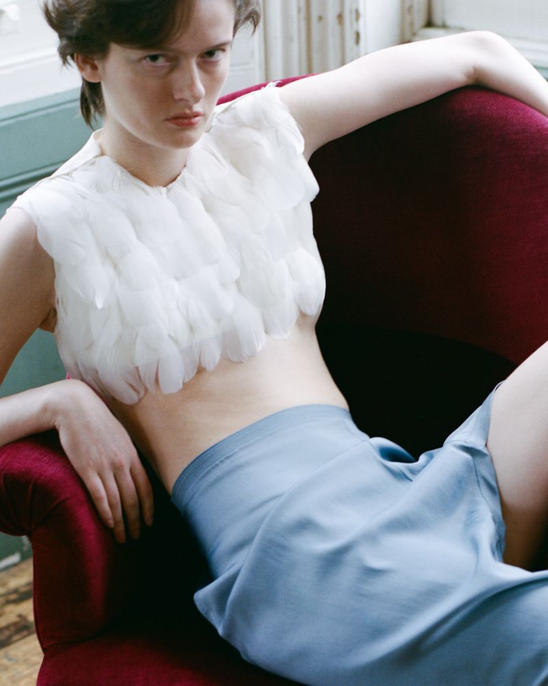 Model seated in a dark red armchair wearing a textured white top and light blue skirt for a Vogue Czechoslovakia editorial