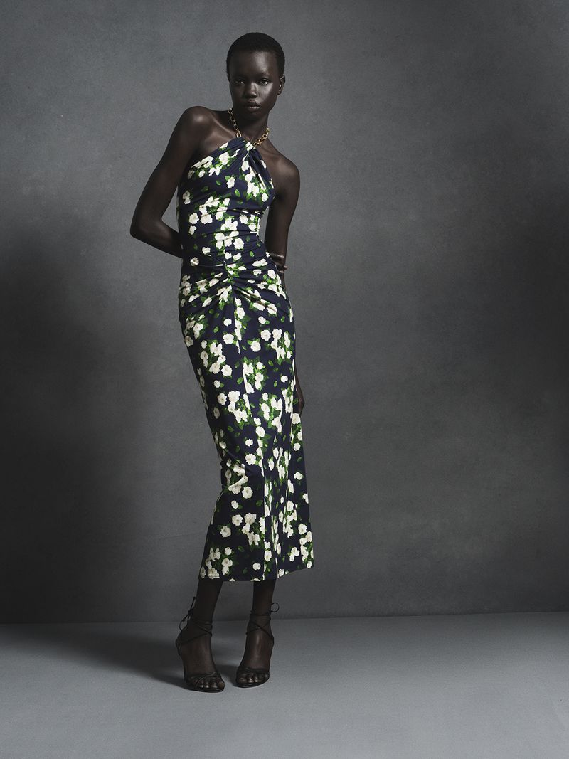 Model in a floral halter-neck midi dress posing against a grey studio backdrop for Carolina Herrera.