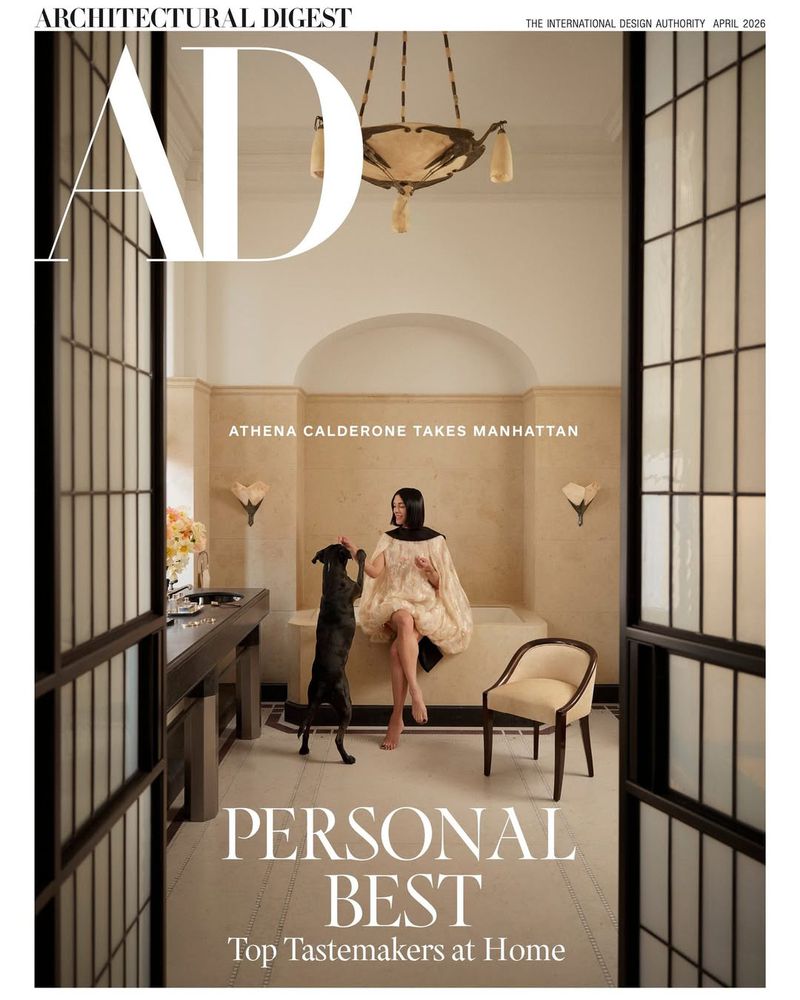 Architectural Digest cover featuring a woman in a dress sitting next to a black dog in an elegant interior with a chandelier.