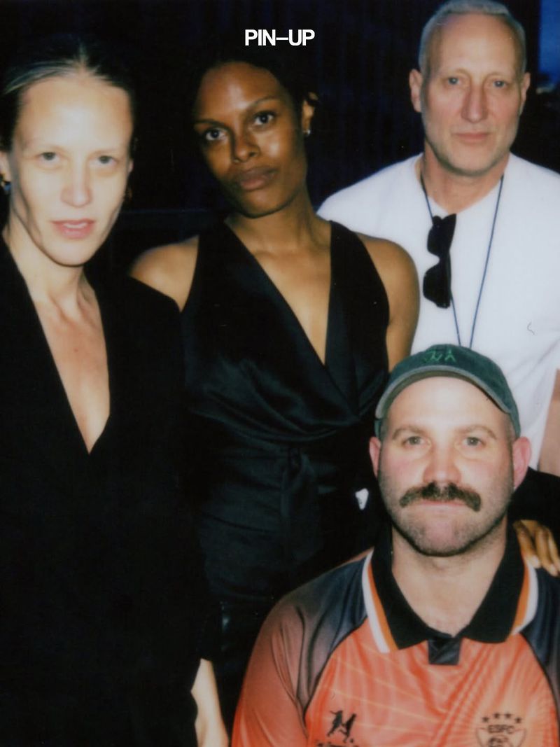 Group portrait of four people posing together for a PIN-UP Magazine project in a dimly lit indoor setting.