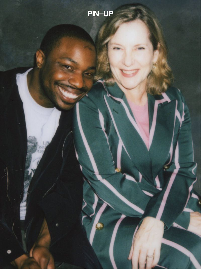A smiling Black man leaning on a smiling white woman wearing a dark green striped suit for PIN-UP Magazine