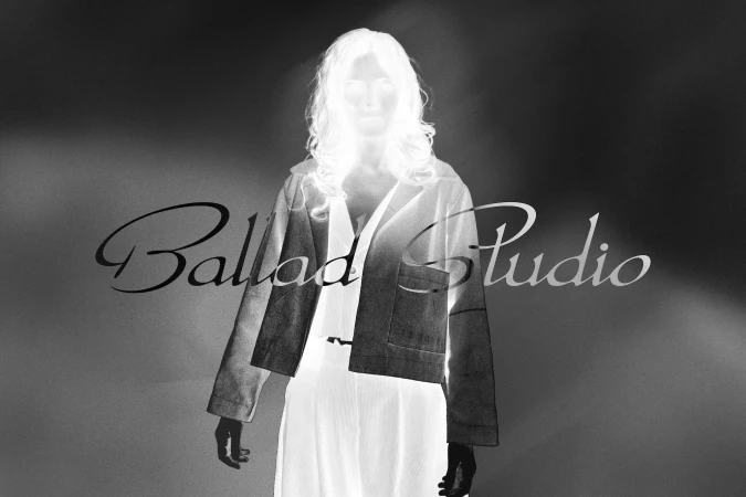 Monochrome inverted portrait of a woman wearing a jacket with flowing text overlay for Ballad Studio brand identity.