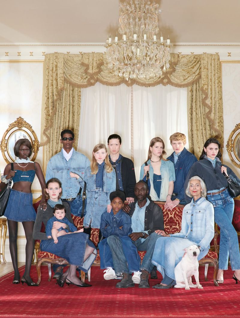 Group portrait of diverse models posing in all-denim outfits within a grand interior setting featuring a crystal chandelier.