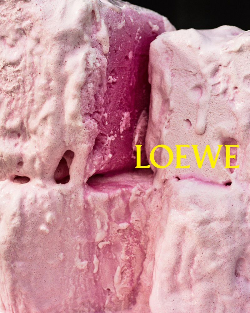Abstract close-up of pink block-like objects covered in a white, icing-like substance, with the text “LOEWE” overlaid in yellow.