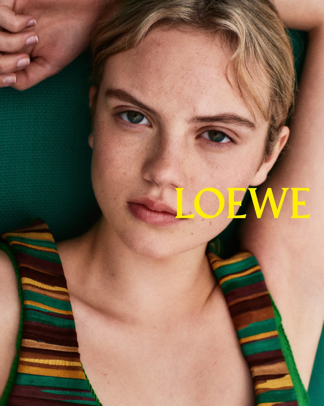 Close-up portrait of actor Isla Johnston in a striped green and yellow top for Loewe Fall/Winter 2026 Precollection.