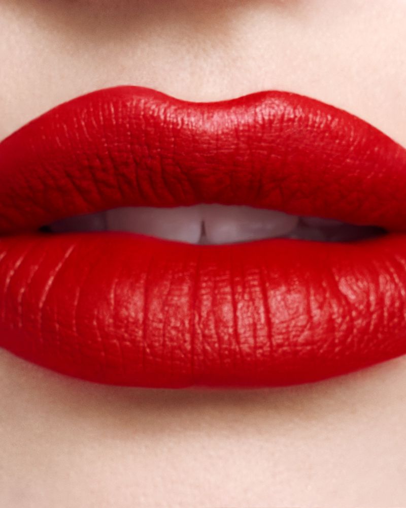 Close-up macro shot of lips wearing vivid matte red lipstick with visible lip texture