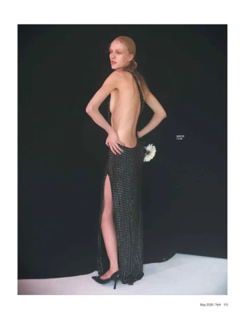 Model in a black sequin backless evening gown with a high slit against a dark background