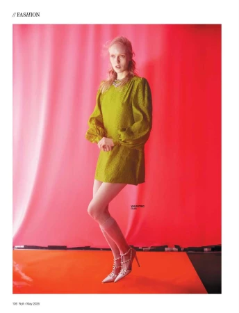 Model in a green dress and heels posing against a vibrant red backdrop for SCMP Style