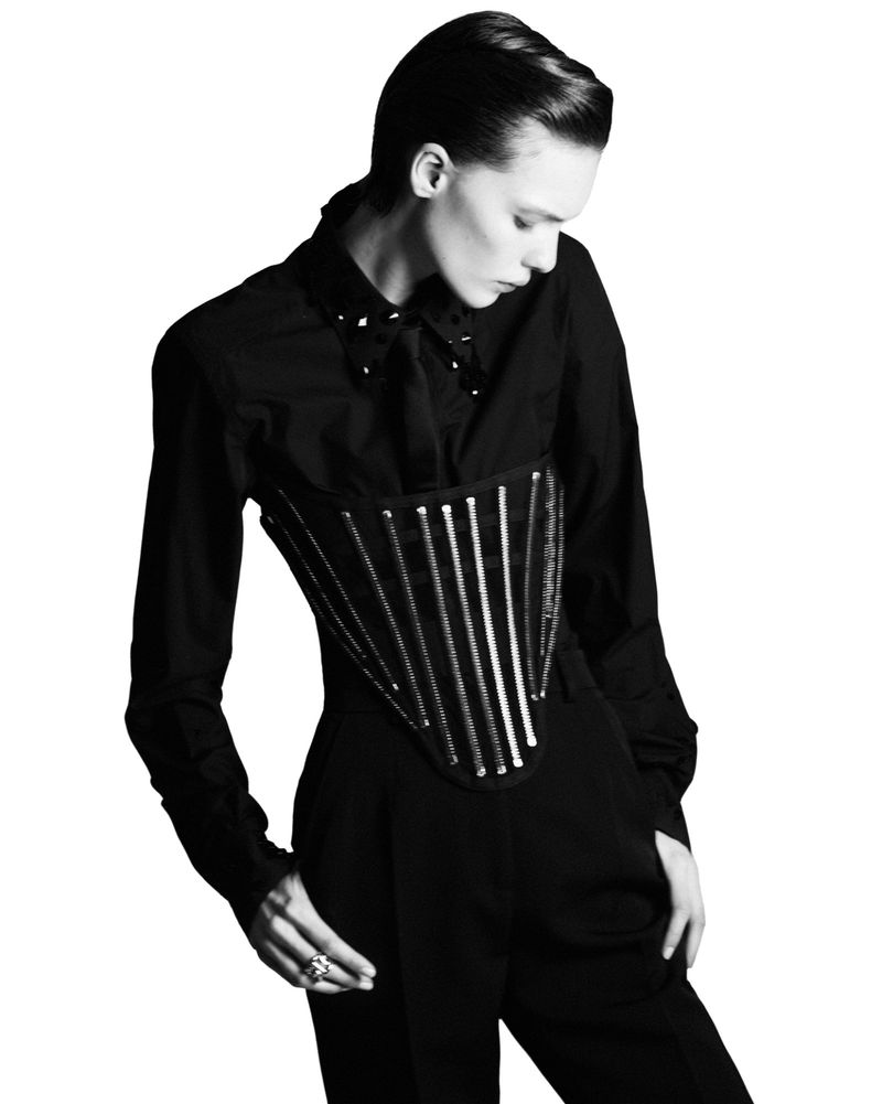 Model Penelope Ternes wearing a black structured corset over a shirt and trousers against a white seamless background