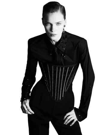 Model Penelope Ternes wearing a black embellished shirt and corset against a white background