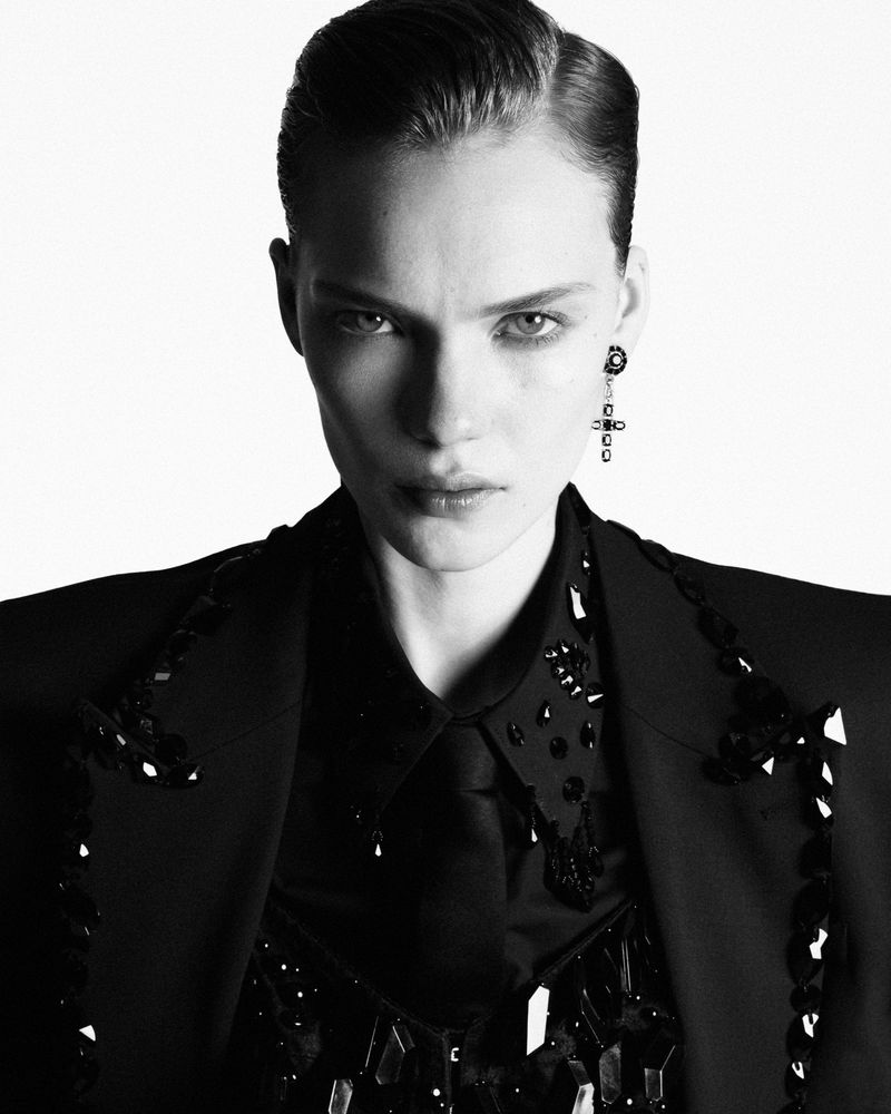 Model Penelope Ternes wearing an embellished black jacket and shirt against a plain white background in a studio portrait.