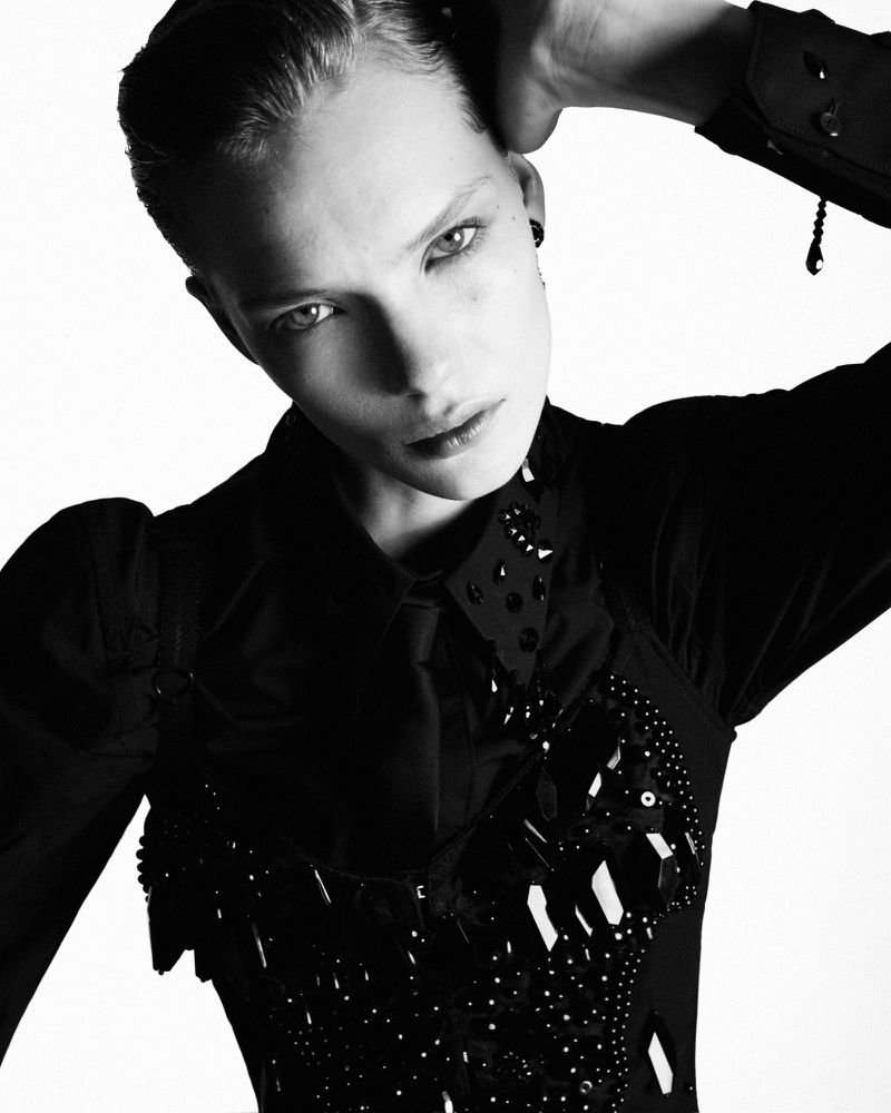 Monochrome portrait of model Penelope Ternes posing in a dark embellished top against a white backdrop.