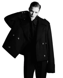 Model Penelope Ternes wearing a black double-breasted coat and trousers against a white background.
