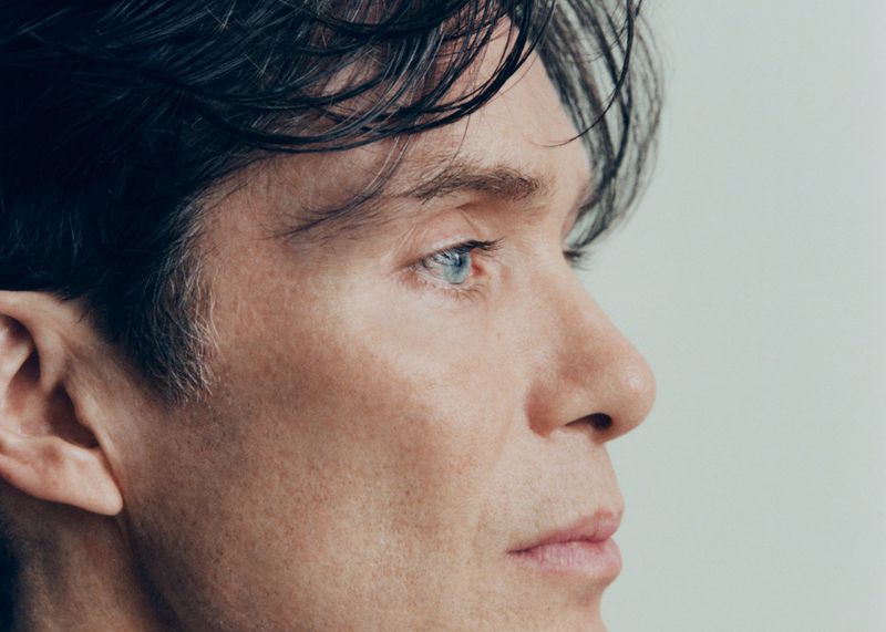 Close-up portrait of an adult male with blue eyes and dark hair. The man faces right against a plain, light background with natural lighting.