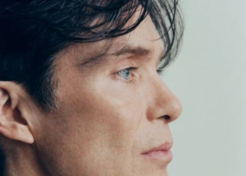Close-up profile portrait of actor Cillian Murphy with dark hair and blue eyes against a light background for GQ Poland.