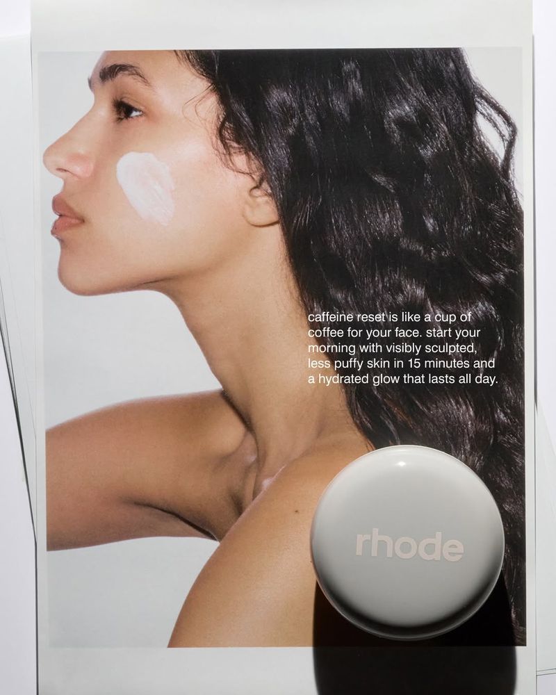 Profile portrait of a woman with dark wavy hair and white skincare cream on her cheek for rhode Skin