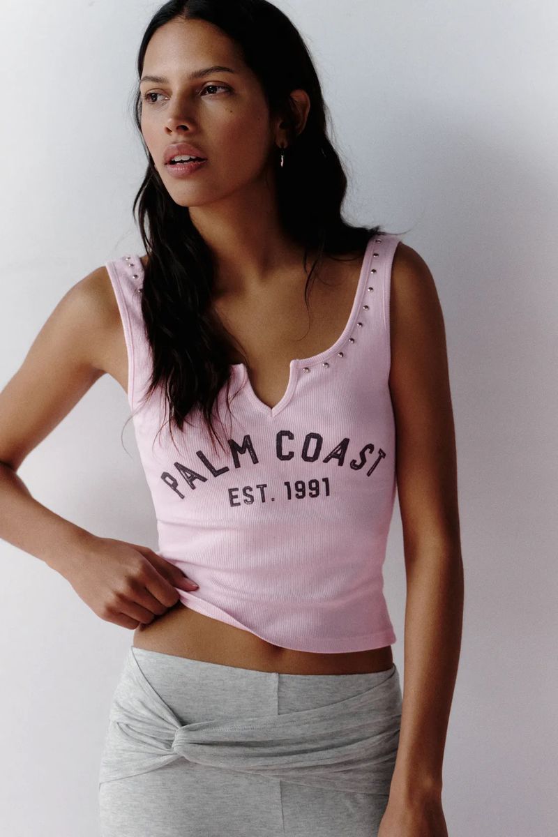 Model wearing a pink graphic tank top and grey skirt against a neutral background for Pull and Bear