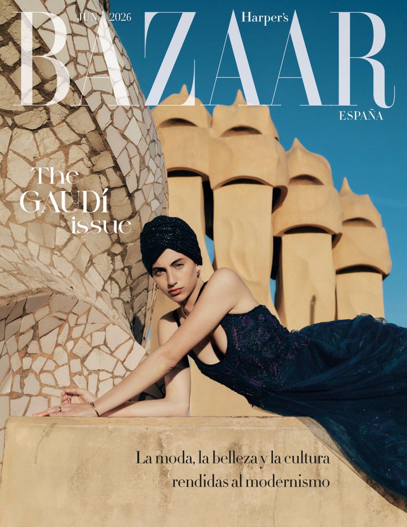 Model in dark blue dress and matching turban leaning against modernist architecture in Barcelona