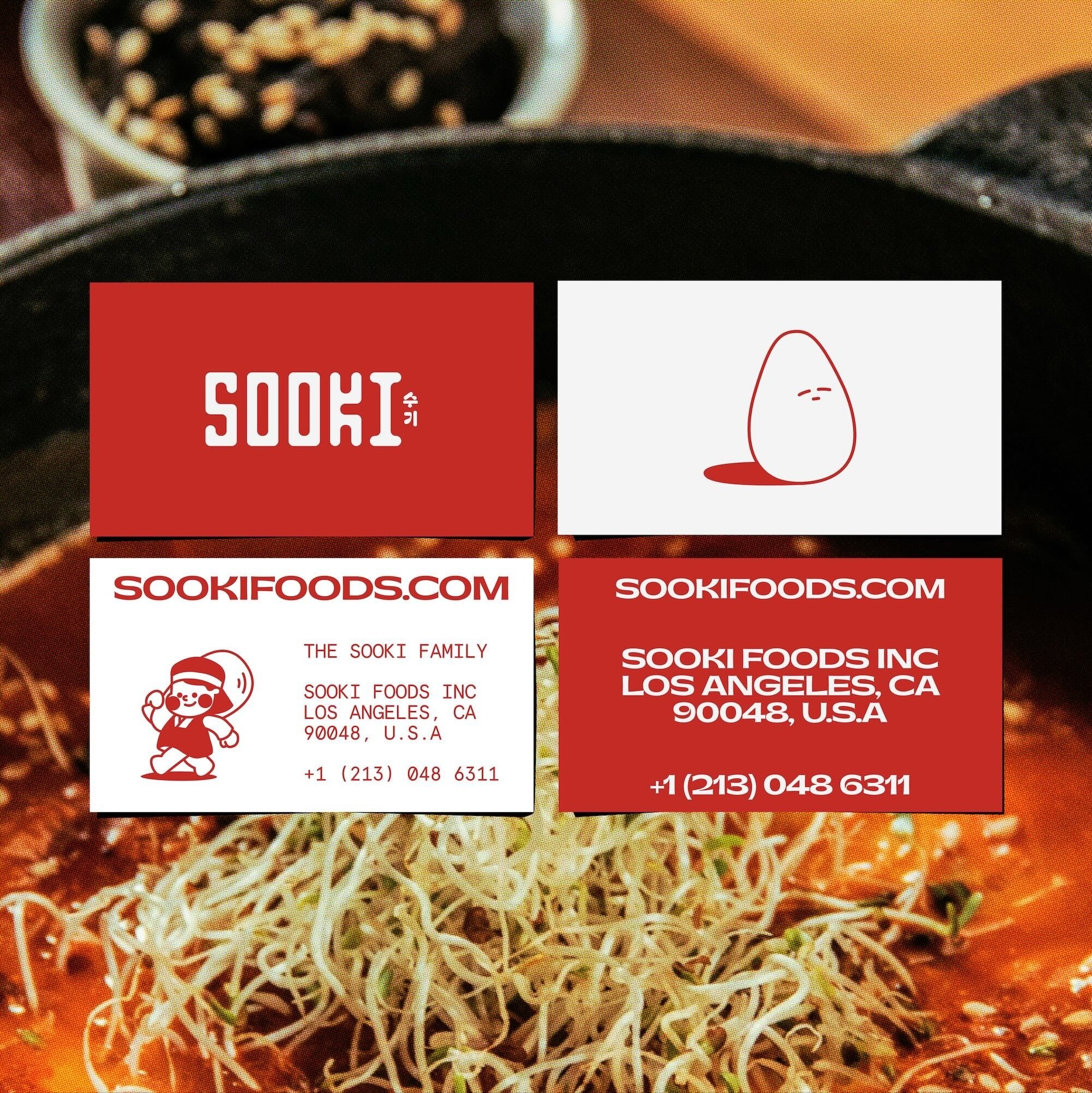 Close-up of food over business cards for Sooki Foods INC, Los Angeles. Cards show contact details and a cartoon egg illustration.
