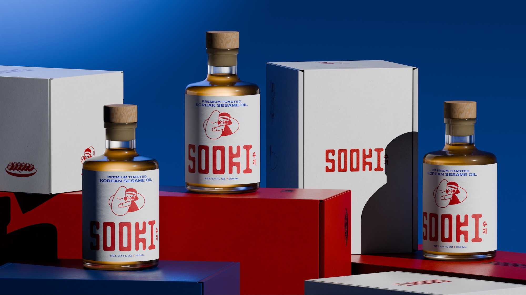 Product packaging showcase featuring four glass bottles of Sooki sesame oil and branded boxes on red and blue pedestals.