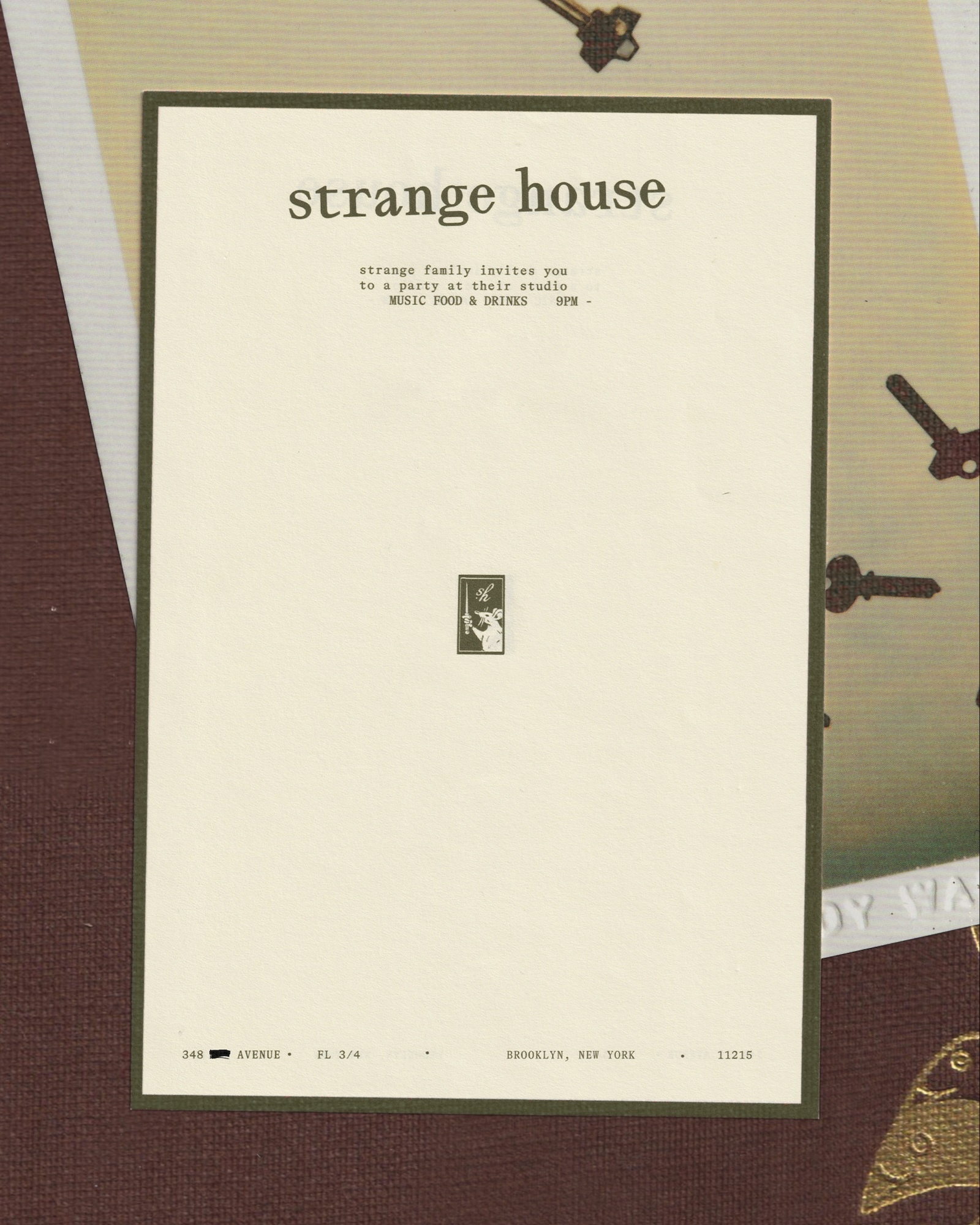 Cream-colored paper invitation card with typewriter typography centered on a patterned surface with keys