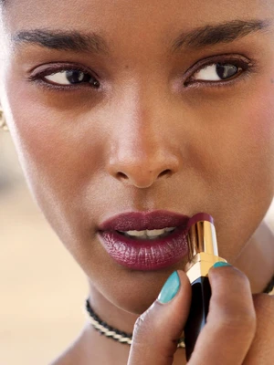 Close-up portrait of model Malika Louback applying deep berry lipstick for Chanel Beauty Les Beiges campaign