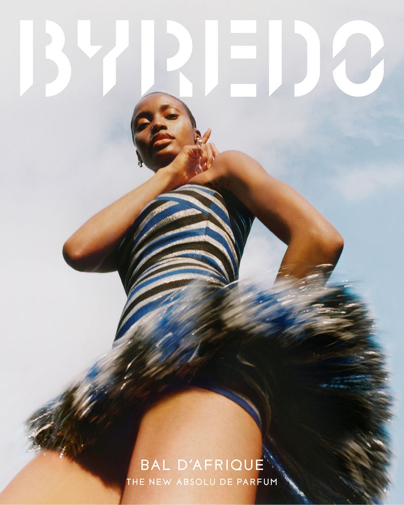 Model in a striped dress captured from a low angle against a clear sky for Byredo Bal d'Afrique campaign