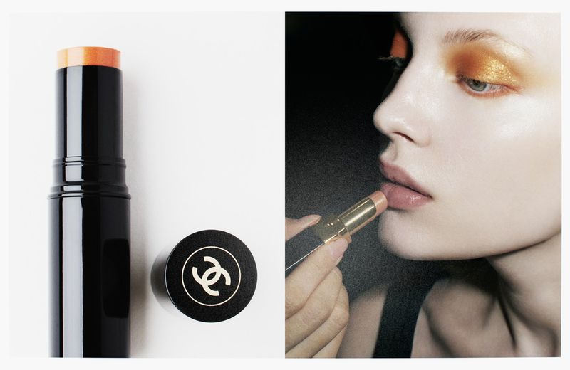Chanel makeup advertisement featuring a woman applying a golden lipstick with matching eyeshadow on a dark background.