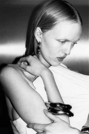 Close-up monochrome portrait of a woman wearing metallic chunky bracelets against a metallic background for Cero Magazine.