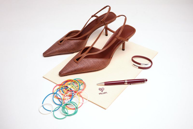 Brown slingback heels arranged on a card with colourful rubber bands and a pen for Family Style