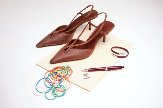 Brown slingback heels arranged on a card with colourful rubber bands and a pen for Family Style