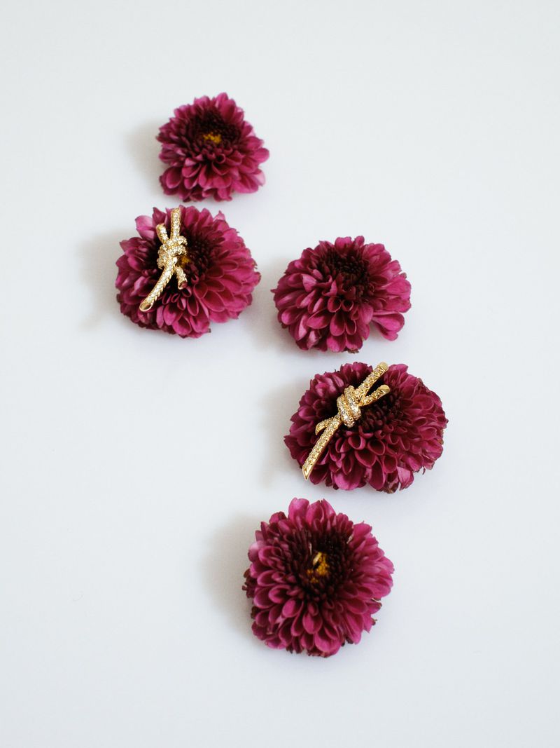 Five deep purple chrysanthemum flowers arranged vertically on a clean white background with gold ribbon accessories