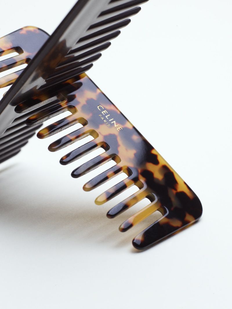 Close-up of two tortoiseshell hair combs interlocking against a plain white background with visible branding.