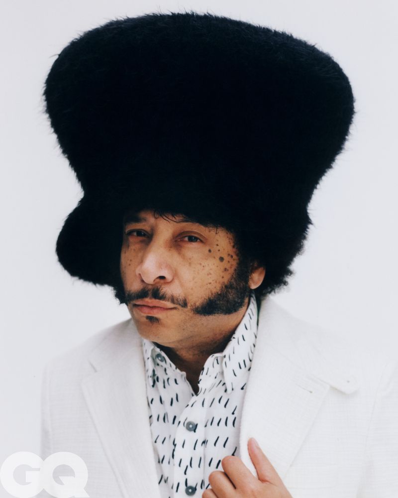 Boots Riley wearing an oversized black furry hat and white patterned shirt for GQ Magazine U.S. portrait