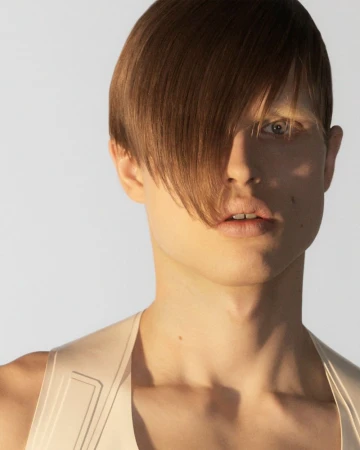 Close-up portrait of a male model with side-swept brown hair against a white background, photographed by Karl Felix.