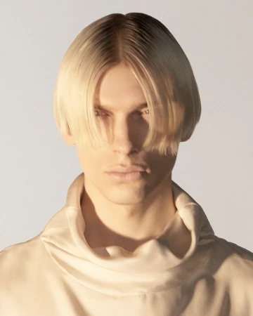 Close-up portrait of a male model with blonde hair wearing a cream turtleneck against a plain white studio background.
