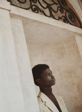 Model in cream blazer and dark top leaning against neoclassical architectural pillars for Prada ICON Magazine Mena editorial