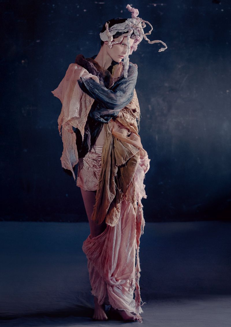 Model Saskia de Brauw draped in textured layered fabrics against a dark mottled background for Luncheon Magazine editorial