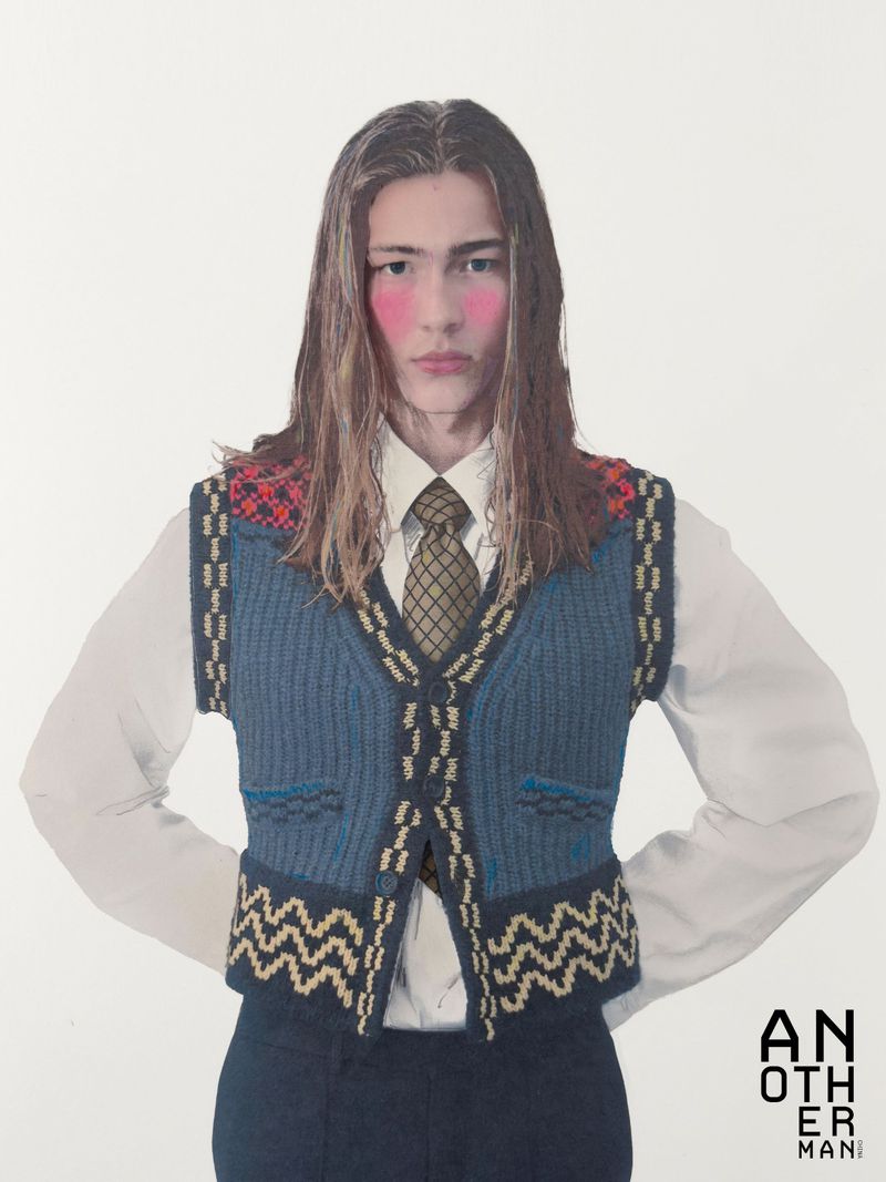 Model with long hair wearing a blue patterned sweater vest and tie against a plain white background for AnOther Man China